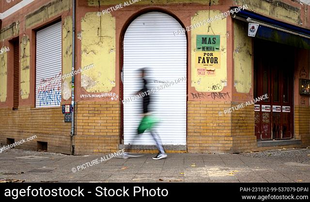 PRODUCTION - 09 October 2023, Berlin: A man walks past an abandoned pub in need of renovation in the Neukölln district. (to dpa ""on the long-term study ""The...
