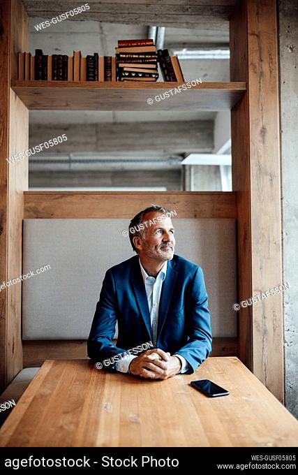 Thoughtful male entrepreneur looking away while sitting by table