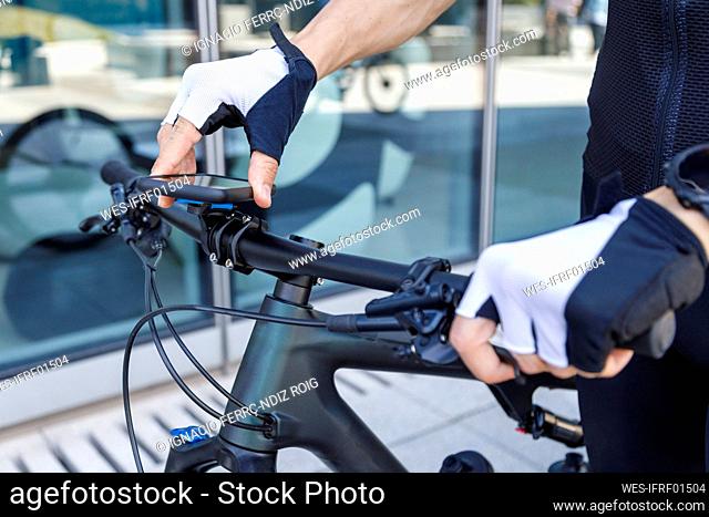 Young man adjusting smart phone on bicycle handlebar