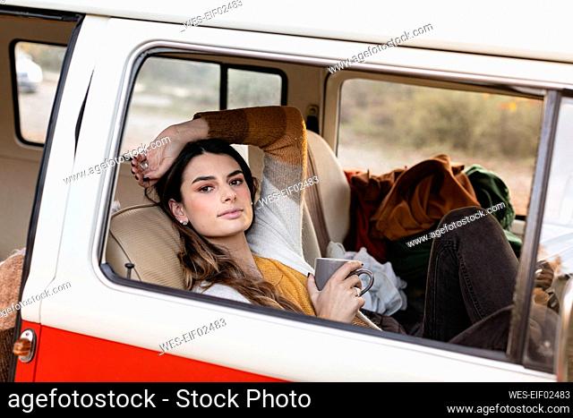 Young woman having coffee in van