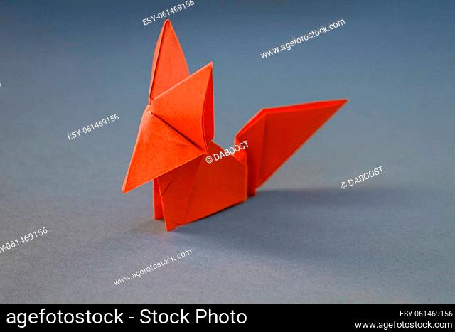 Orange paper fox origami isolated on a blank grey background