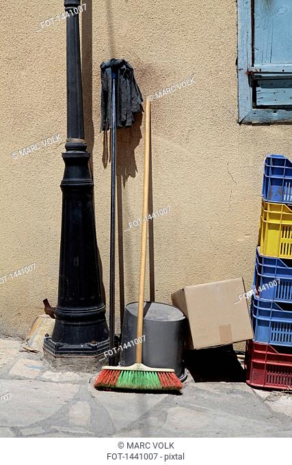 Mop and broom by containers against wall