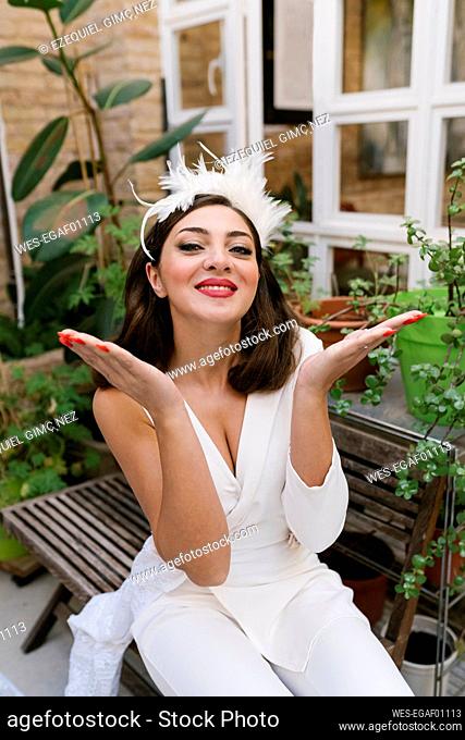 Happy young bride giving flying kiss in garden against plants