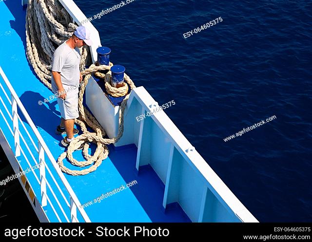 Agiokampos, Evia island, Greece - August 15, 2023: Worker on ferryboat tying rope at Evia island in Greece