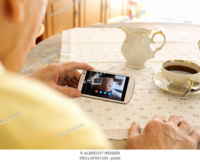 Grandfather videoconferencing with pregnant granddaughter via smartphone