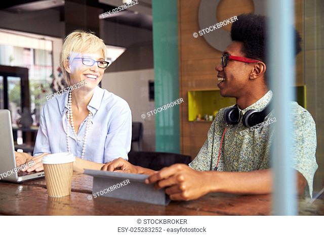 Two Young Businesspeople Working On Laptop In Coffee Shop