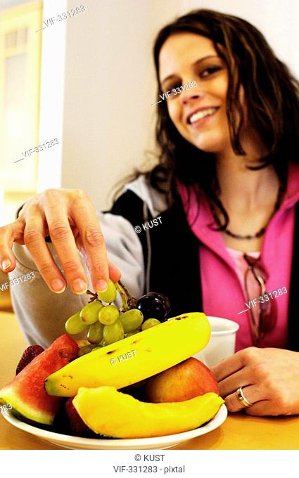 Junge Frau erfreut sich am gesunden Geschmack unterschiedlicher Obstsorten. - Purgstall, Niederoesterreich, Austria, 21/04/2005