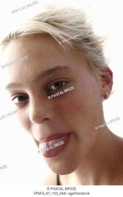 Portrait of a young woman showing her tongue stud