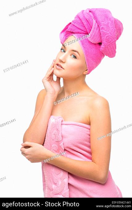 Beautiful young woman with hair and body wrapped in pink towel. Isolated over white background. Copy space