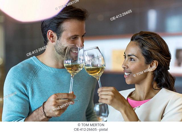 Smiling couple toasting white wine glasses