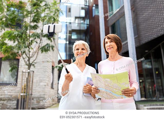 senior women with map and city guide taking selfie