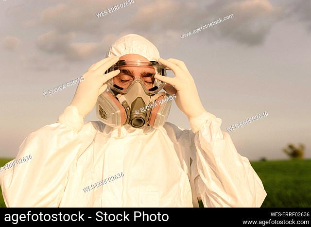 Portait of man with closed eyes wearing protective suit and mask