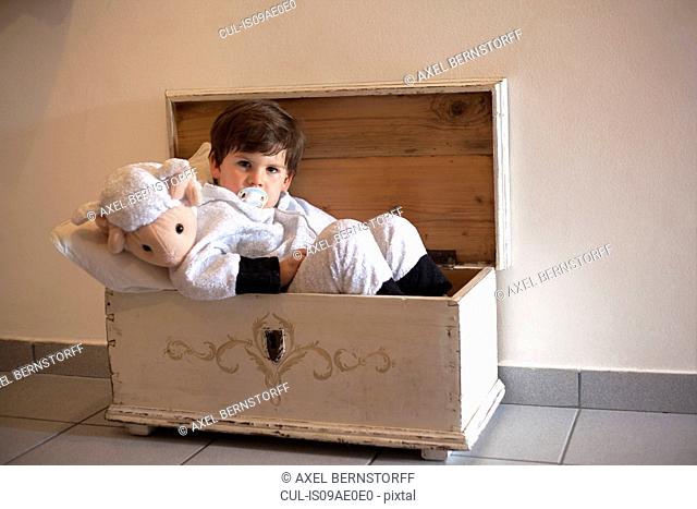Portrait of male toddler ready for bed in small wooden trunk
