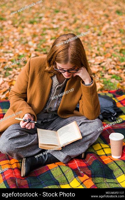 Libro de lectura de mujer joven en el parque de otoño