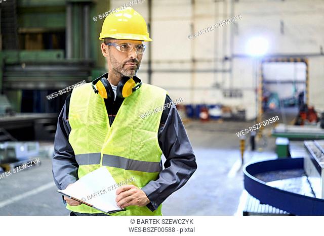 Man wearing protective workwear looking around in factory