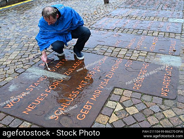 04 November 2021, Brandenburg, Potsdam: An employee of the Office of Public Order cleans the lettering on Luisenplatz to commemorate the fall of 1989