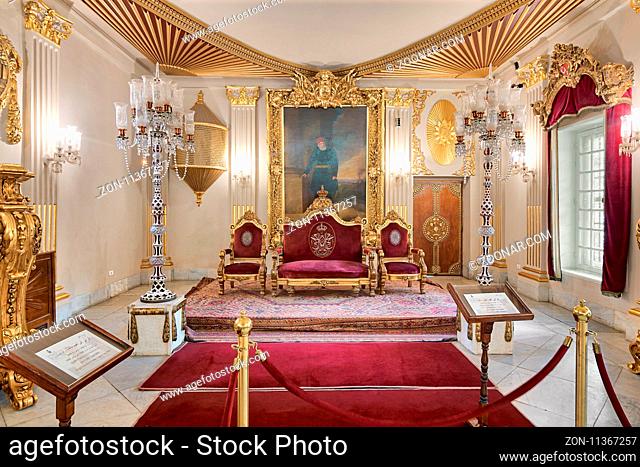 Cairo, Egypt - October 21, 2017: Throne Hall at Manial Palace of Prince Mohammed Ali Tewfik with gold plated red armchairs, antique floor lamps