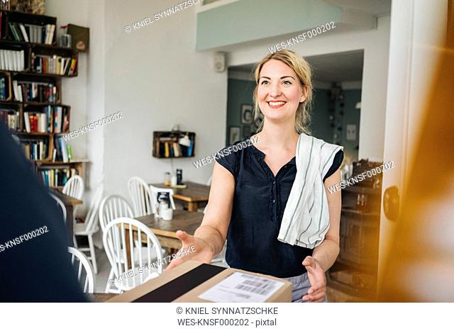 Smiling woman receiving parcel in a cafe