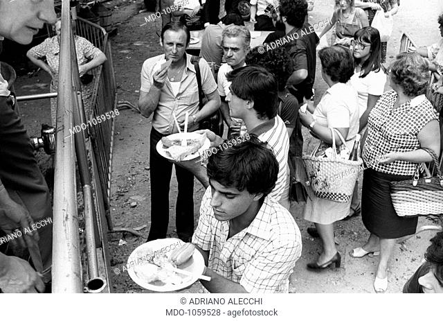 Festa dell'Unità. People attending Festa dell'Unità in Parco Sempione eating outdoors. Milan, September 1979