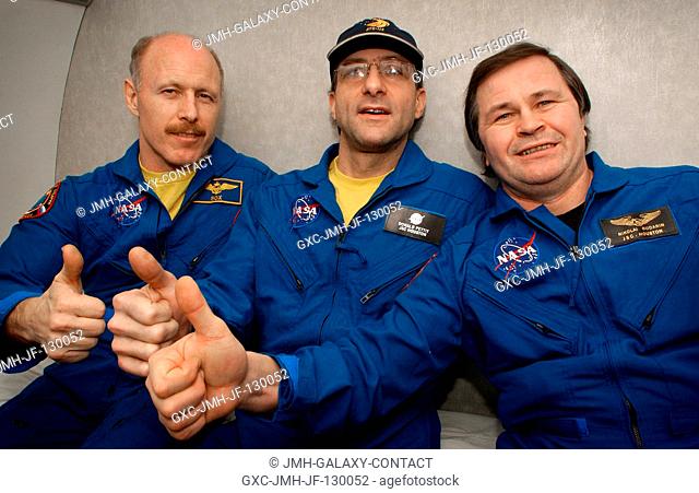 The Expedition Six crewmembers give a thumbs-up signal onboard an aircraft flight from Kazakhstan to Moscow after their Soyuz capsule landing