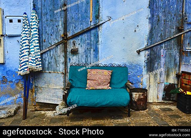 Green sofa in front of blue doors, Sofa with parasols in alley of Chefchaouen, Blue City, Chefchaouen, Tangier-Tétouan-Al Hoceïma, Morocco, Africa