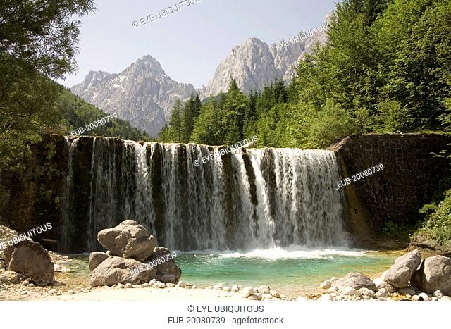 A waterfall on Velika Pisnica with Mounts Razor and Prisank in the Julian Alps in the background. There is still snow lying on the mountain after a severe...