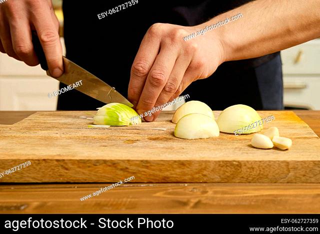 Closeup view of cutting onion. Male hands with knife sliceing onion