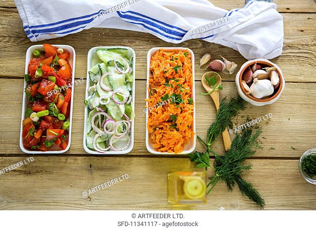 A trio of vegetable salads on a rustic wooden table