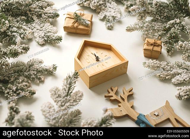 Christmas and New Year still life. Wooden clock shows five minutes to midnight. Fir branches and boxes around
