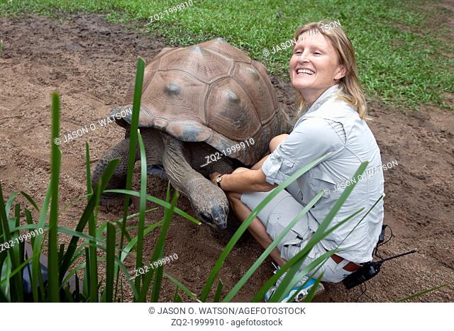 A female zoo worker smiling next to a Aldabran Giant Tortoise (Aldabrachelys gigantea), The Australia Zoo, Beerwah, Queensland, Australia