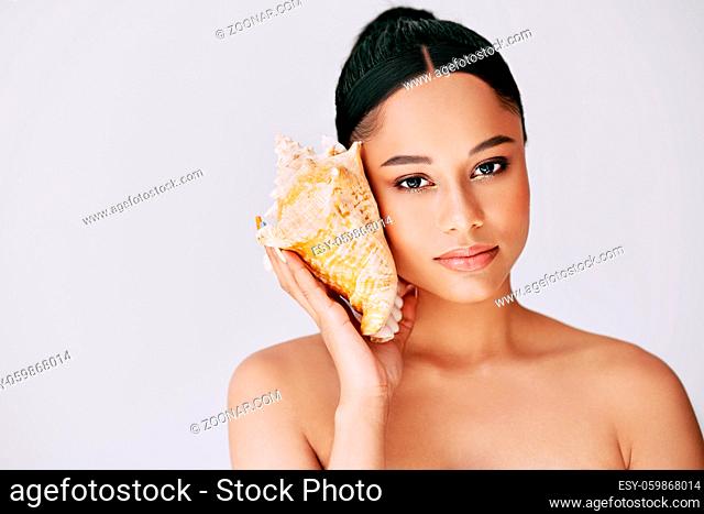 Pretty african american woman pressed conch seashell to her ear enjoy and dreams with copy space for text. Summer vacation and spa relaxation concept