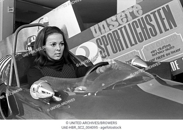 Die deutsche Sängerin Friedel Frank in einem Rennwagen in einem Autohaus in München, Deutschland 1960er Jahre. German singer Friedel Frank sitting in a racing...