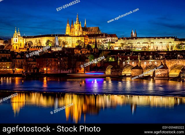 Prague Castle, Hradcany reflecting in Vltava river in Prague, Czech Republic at night. Charles Bridge to the right