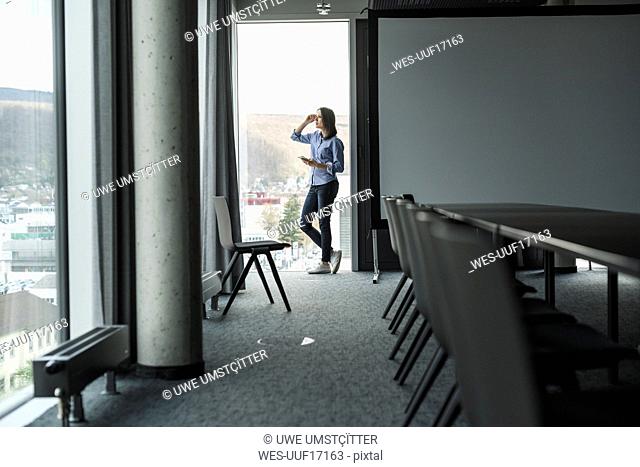 Businesswoman with cell phone standing at the window in office