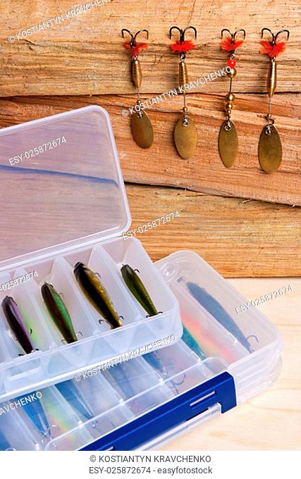 Fishing metal and plastic baits on wooden background. Different kinds of the fishing baits