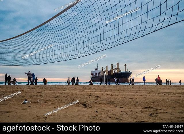 RUSSIA, KRASNODAR REGION - DECEMBER 2, 2023: People on a beach look at the Blue Shark dry cargo ship after it ran aground at the Black Sea resort of Anapa