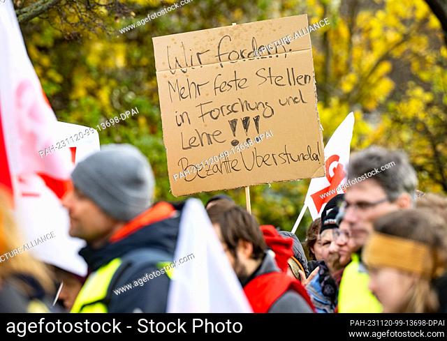 20 November 2023, Saxony, Dresden: Participants stand with a sign ""We demand: More permanent positions in research and teaching! Paid overtime!"" at...