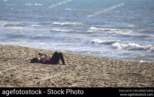 11 December 2023, Spain, Palma: A woman enjoys the sun on the Arenal beach on a sunny day with a record temperature of 24 degrees