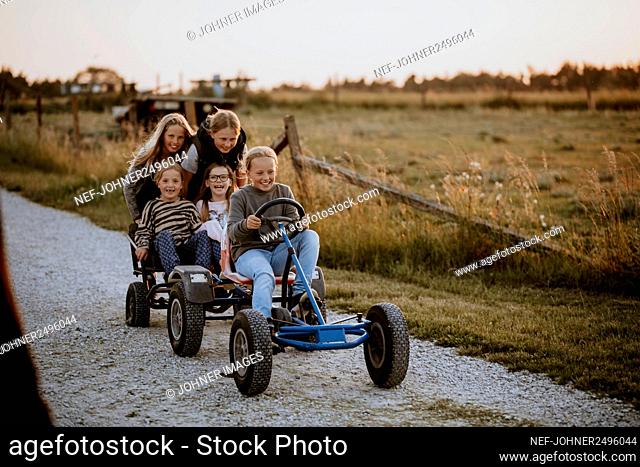 Happy girls riding go-kart on dirt road