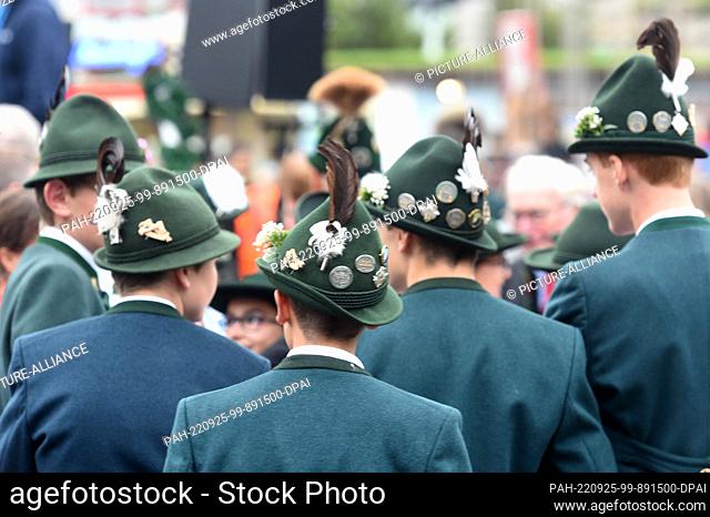 25 September 2022, Bavaria, Munich: Men in traditional costume hats walk across the Theresienwiese at the 2022 Wiesn innkeepers' square concert