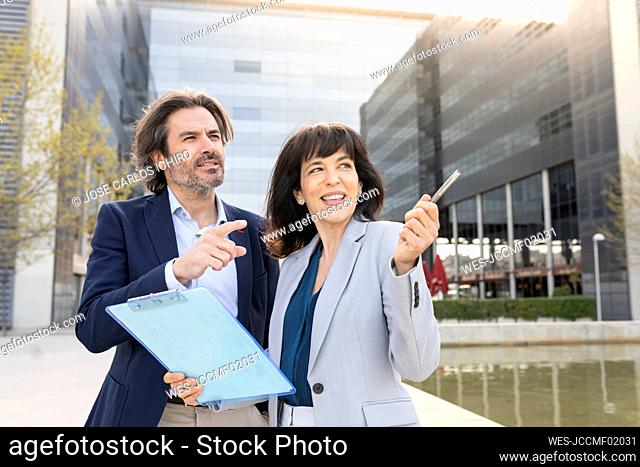 Male and female entrepreneurs pointing while standing in city