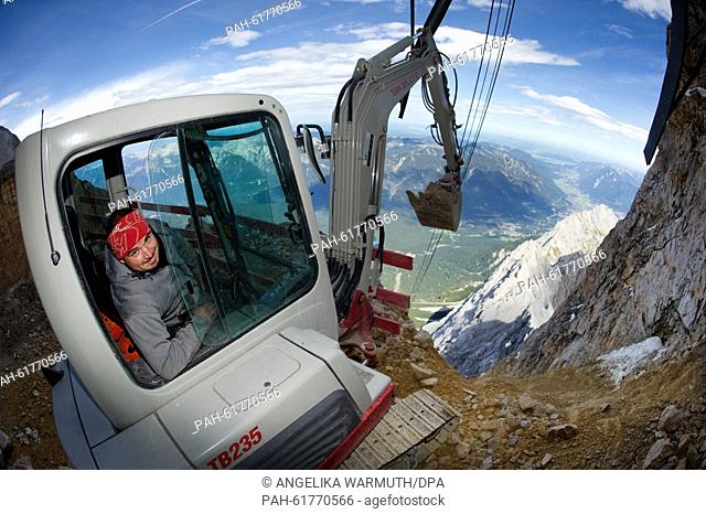 Excavator operator Joachim Strohmeier shovels dirt high above the ground on the Zugspitze mountain near to Grainau, Germany, 16 September 2015
