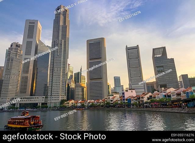Singapore. Quay with cafes and skyscrapers. Pleasure boats. Sunset