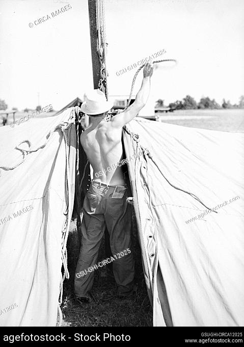 Rear view of carnival crew member at work, Lasses-White traveling show, Sikeston, Missouri, USA, Russell Lee, U.S. Farm Security Administration, May 1938