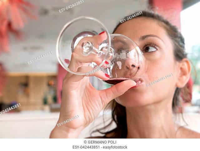 Closeup portrait of young woman with ponytail drinking red wine. Leisure, drinks, degustation, people and holidays concept