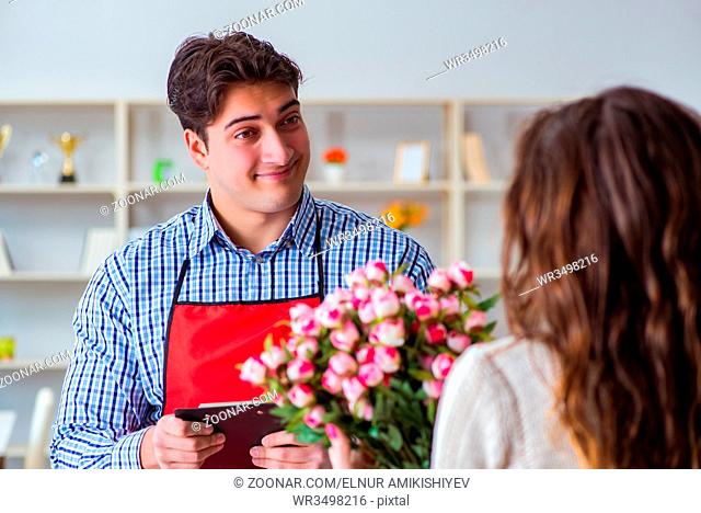 Flower shop assistant selling flowers to female customer
