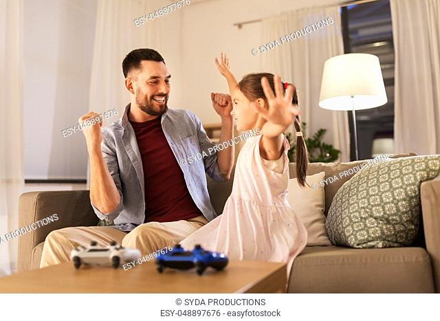 father and daughter playing video game at home