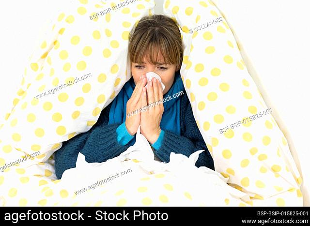 Young woman in bed suffering from a cold with handkerchiefs