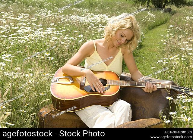 Mid adult woman playing a guitar in a garden