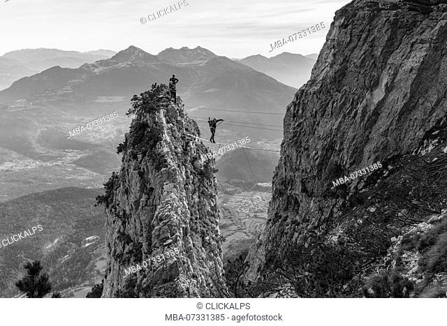 An hiker over a tibetan bridge at via ferrata delle Aquile. Paganella, Trento, Trentino, Italy